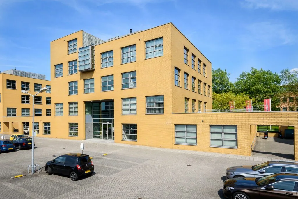 Modern kantoorgebouw aan de Rivium 2e Straat met gele bakstenen en parkeerplaatsen op de voorgrond.